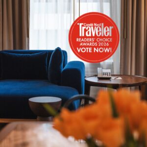A guestroom with a blue couch and orange flowers and the Conde Nast Readers' Choice Awards Logo for 2026