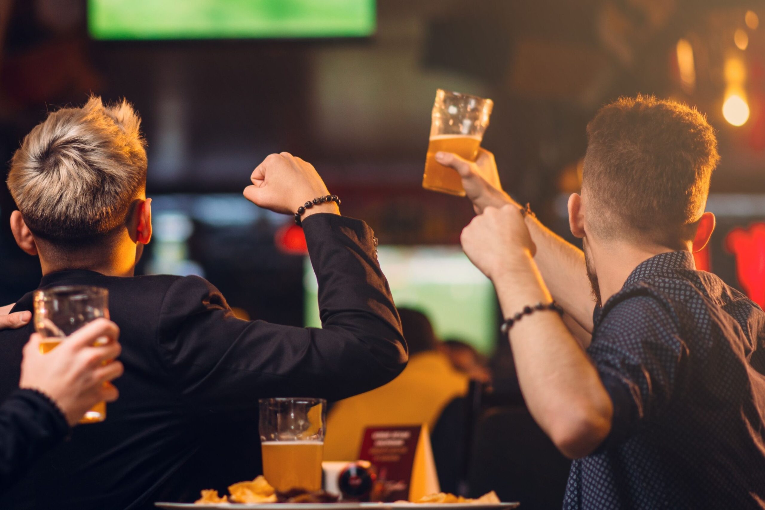Friends cheering a televised game at a Seattle sports bar with pints of beer