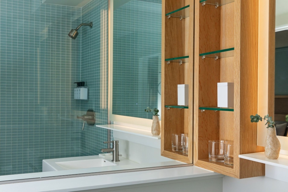 Guestroom bathroom at Hotel Ändra Seattle with glass-tile shower, modern vanity, and wood shelving.