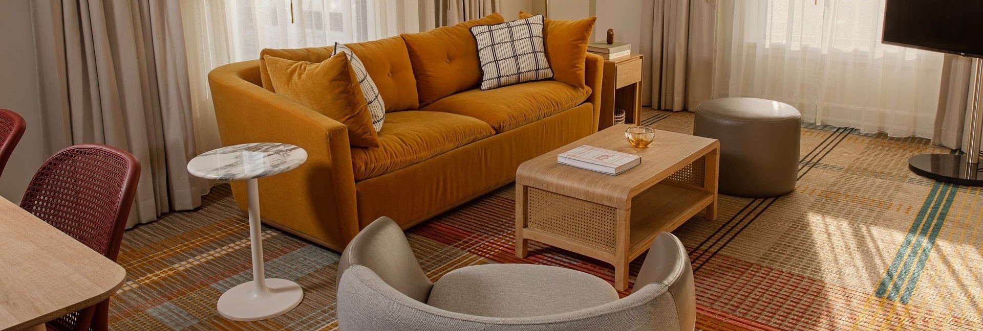 Premier Corner One-Bedroom Suite living room at Hotel Ändra Seattle with mustard sofa, modern chairs, and floor-to-ceiling windows.