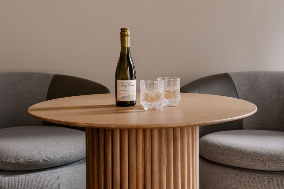 Junior Suite at Hotel Ändra with a modern bed, gray club chairs, round table set with wine and Scandinavian-style wine glasses, ottoman, and large window.